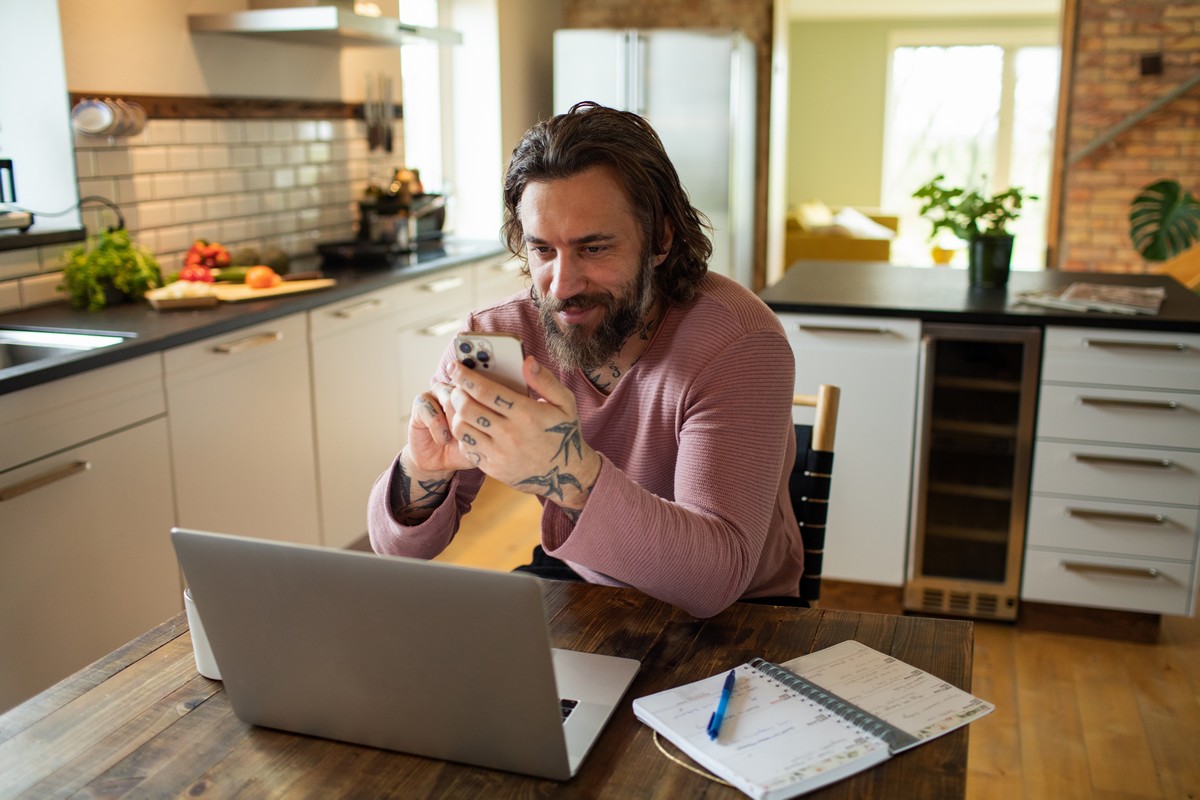 Un homme travaille sur son ordinateur depuis sa cuisine